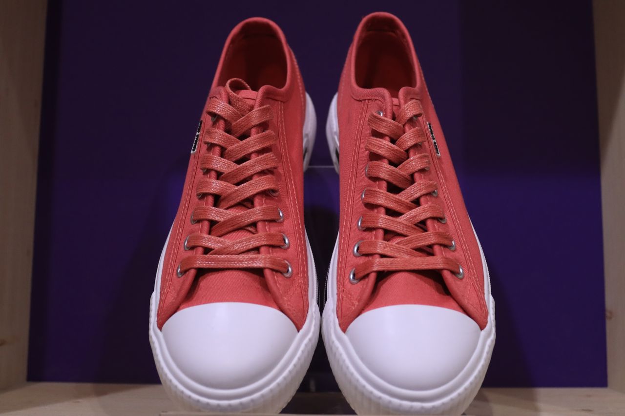 Home Stylish red sneakers with white soles and shoelaces on a display shelf in Jönköping, Sweden.