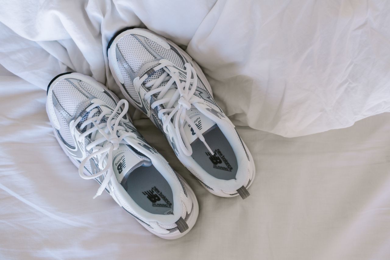 A pair of white sneakers resting on white sheets, captured with soft lighting.