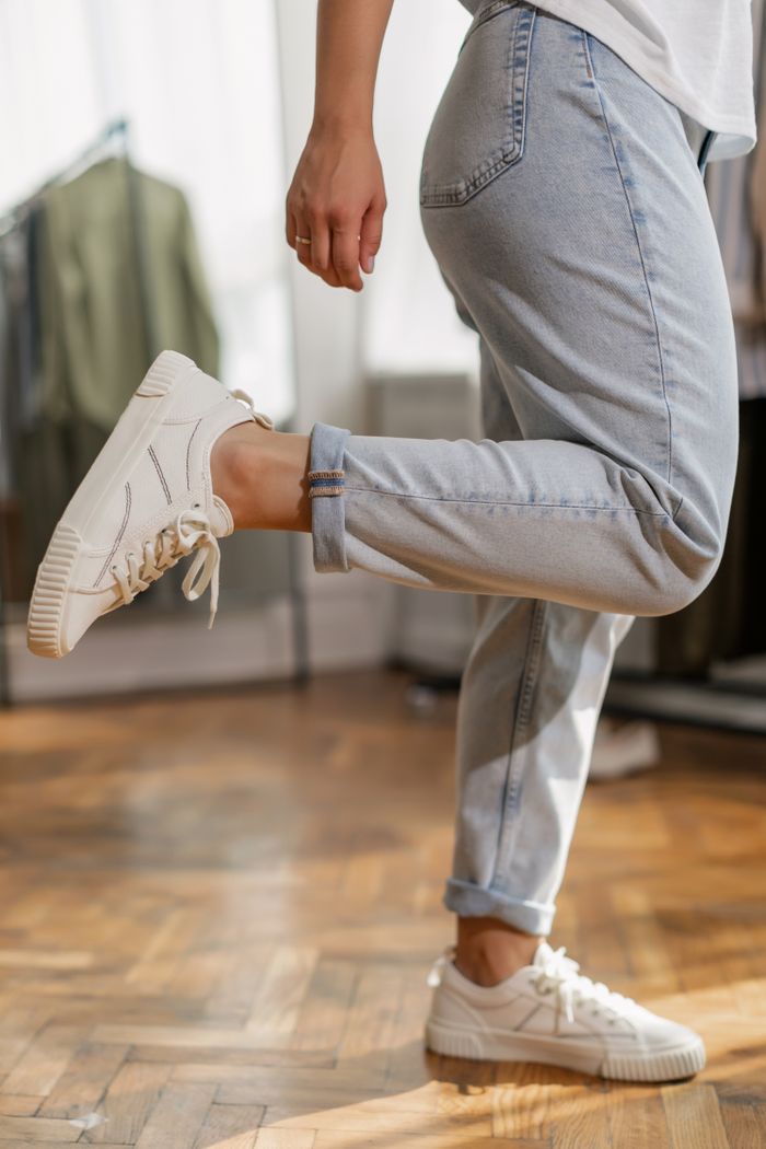 Services Stylish white sneakers paired with rolled-up denim pants, showcasing casual footwear fashion.