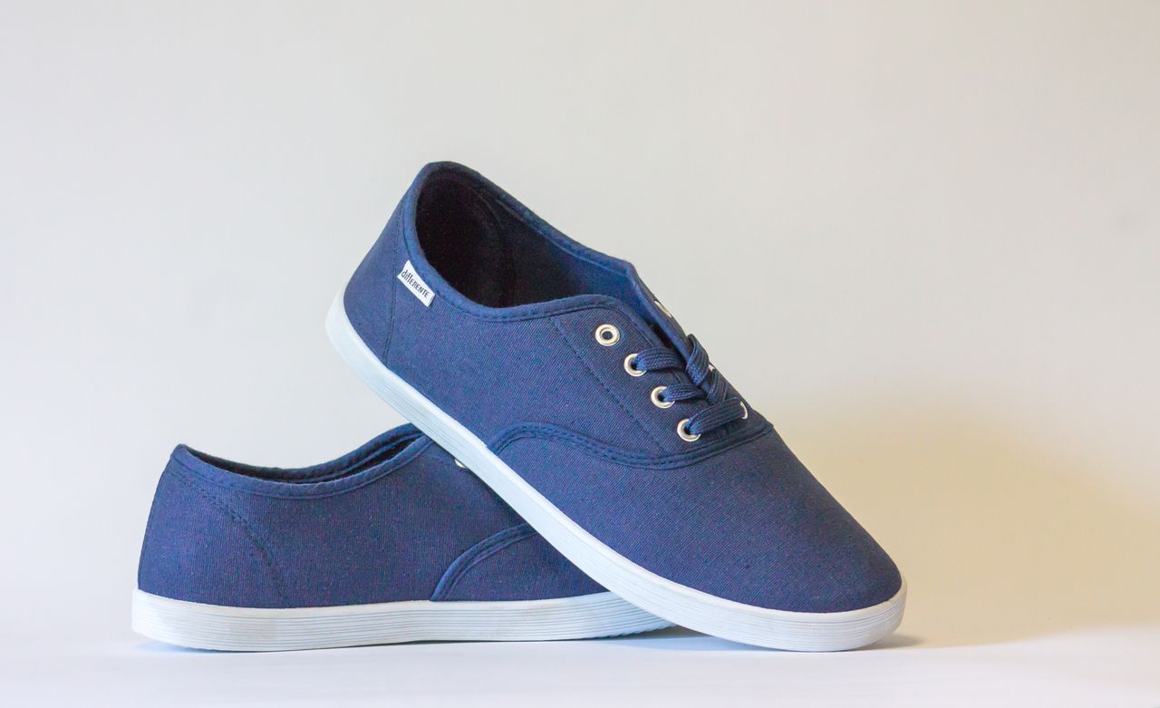 Services Pair of stylish blue canvas shoes with white soles displayed against a neutral background.